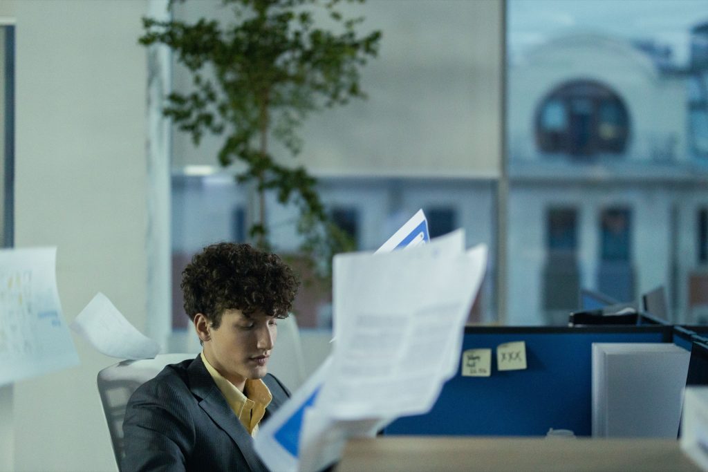 Profesional en una oficina rodeado de papeles y archivadores.
